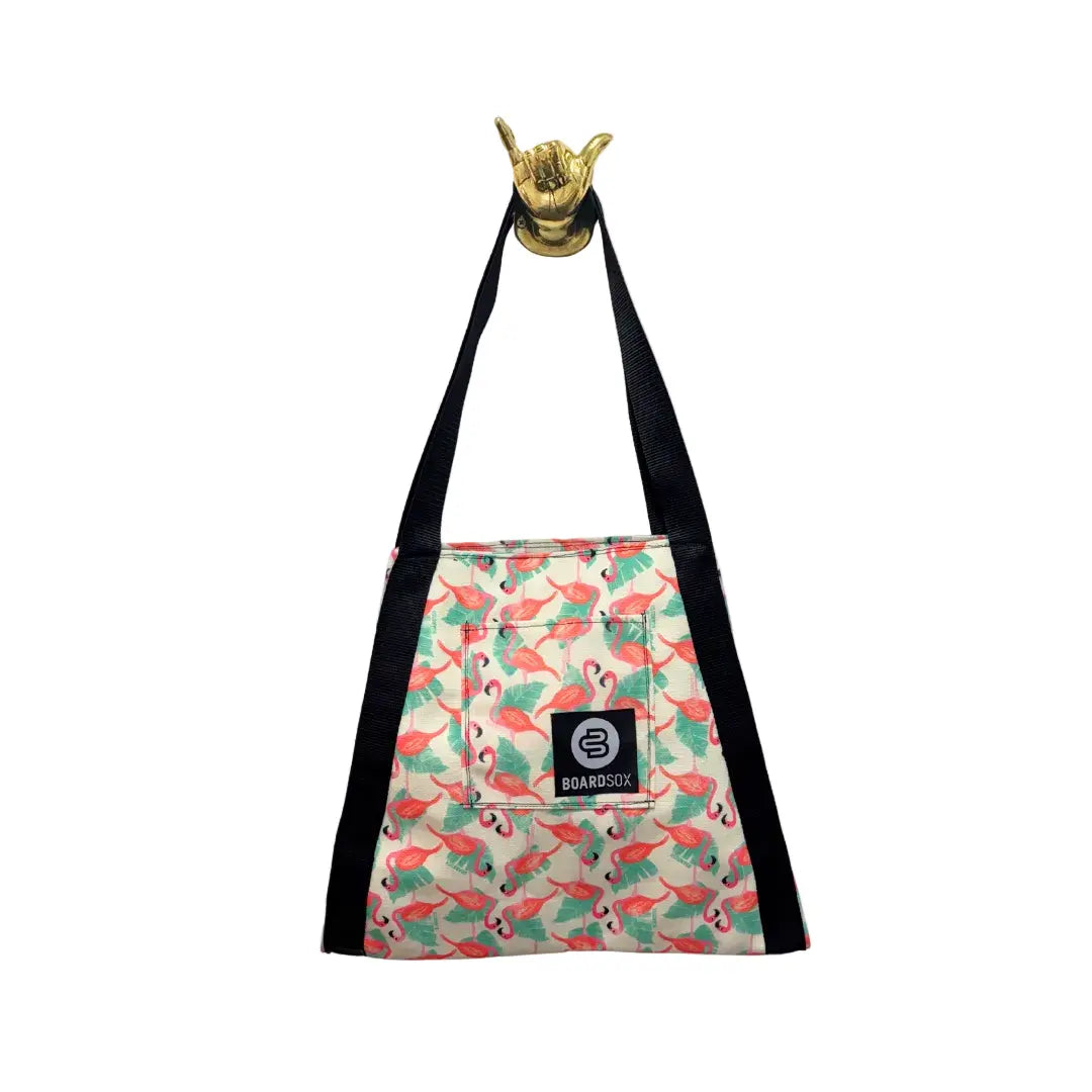 Flamingo-patterned bag with a black strap and gold hand sign on a white background