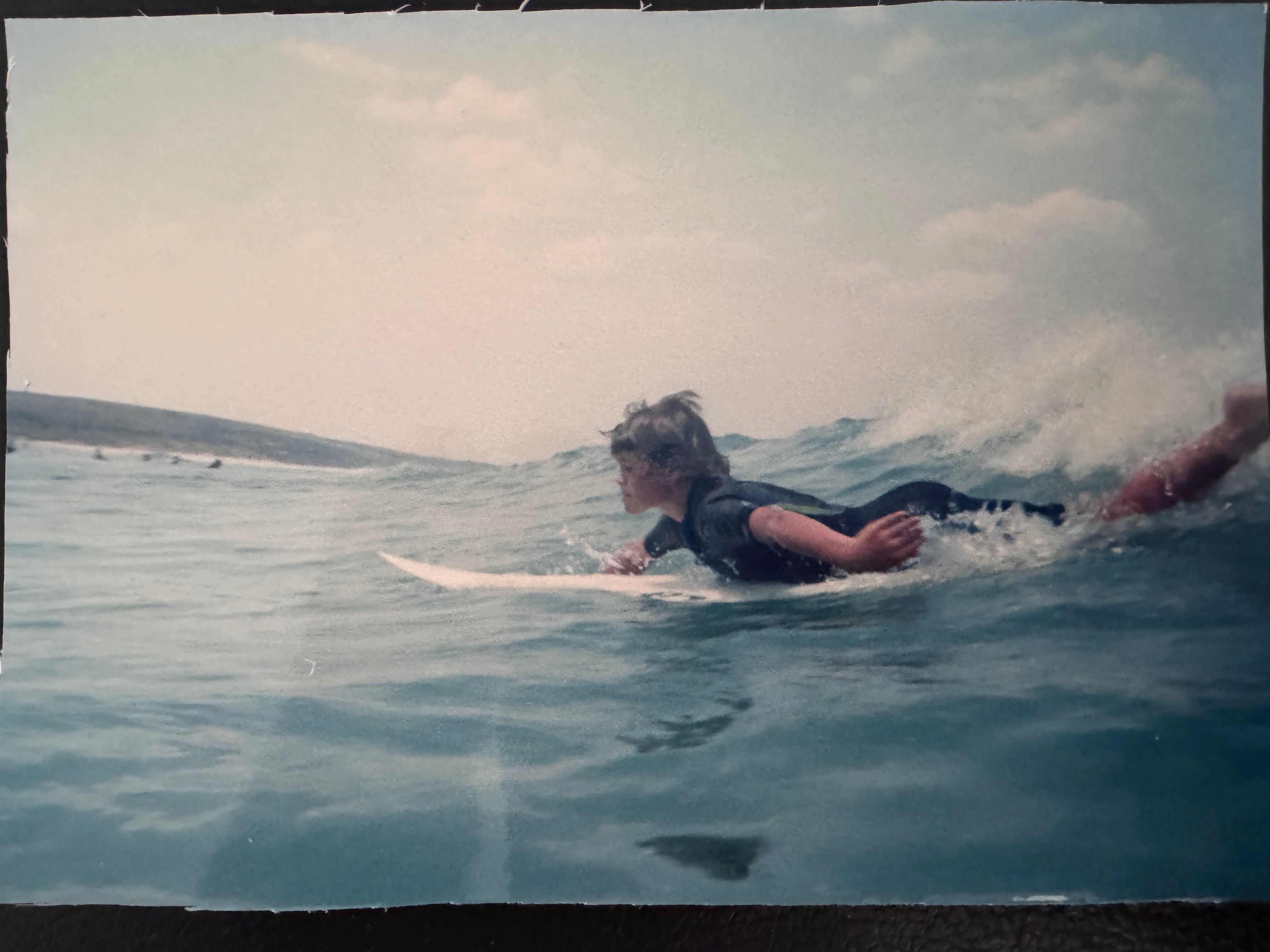 A young grom catching a wave